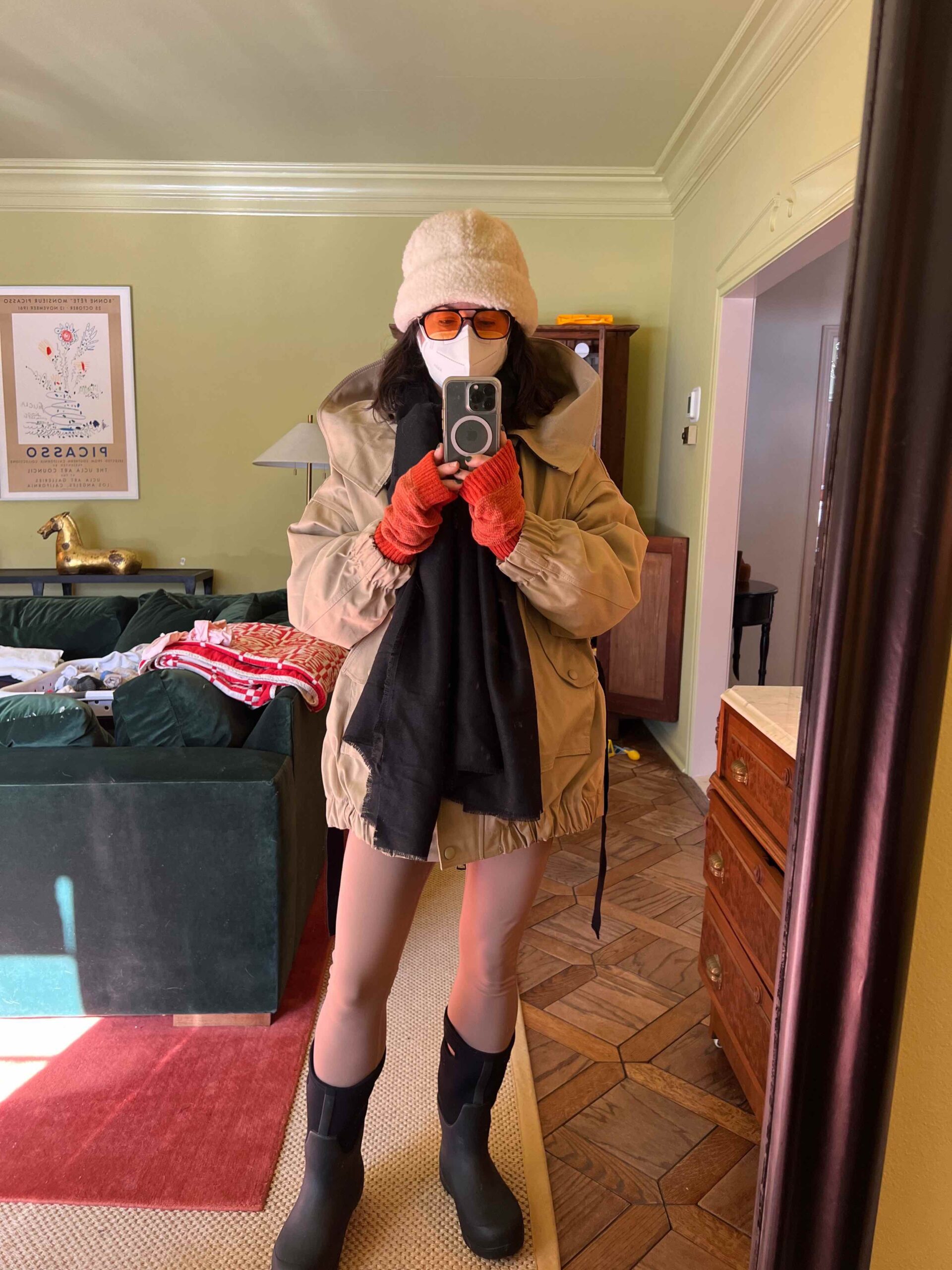 A woman is bundled up and wearing a mask to go for a winter walk outside