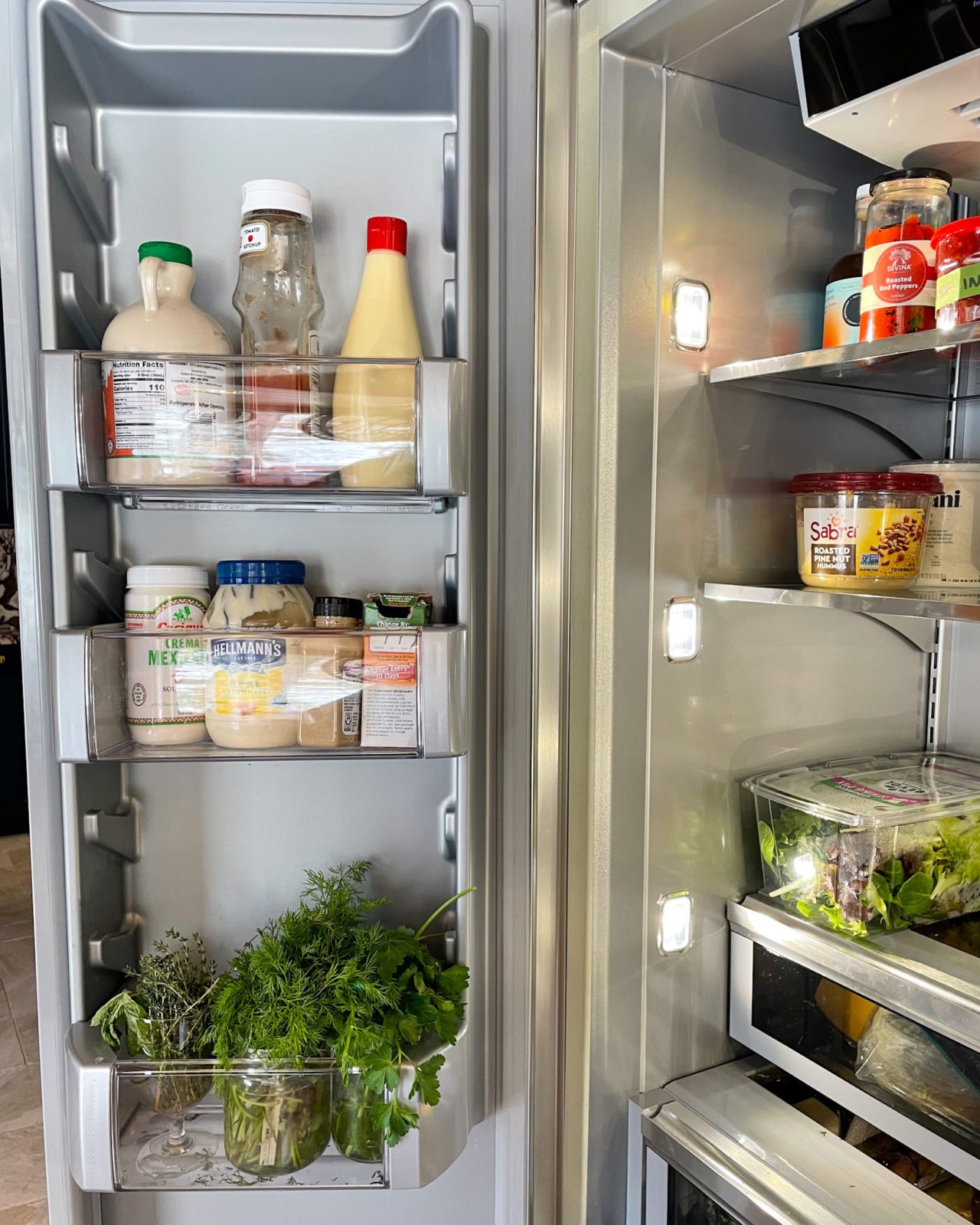 Fridge side shelves with sauces and herbs in glass jars.