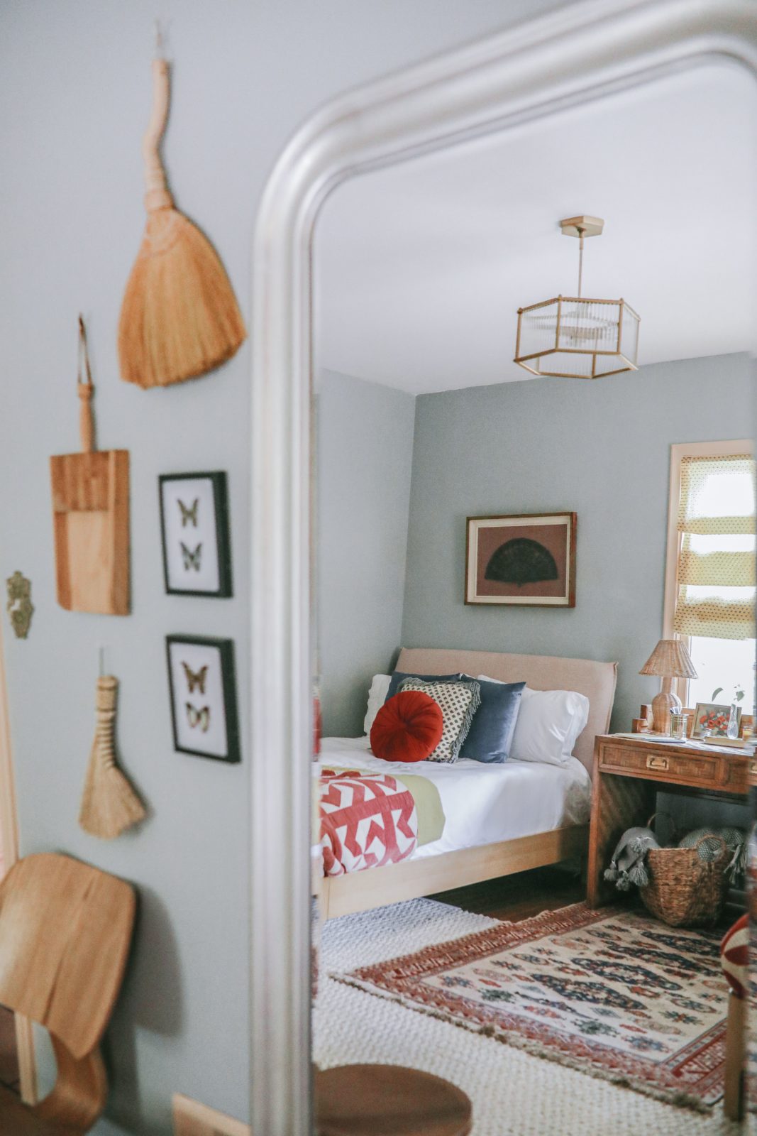 Guest room design. Light blue wall color, layered rugs, Casper bed, antique desk, and art on the walls.