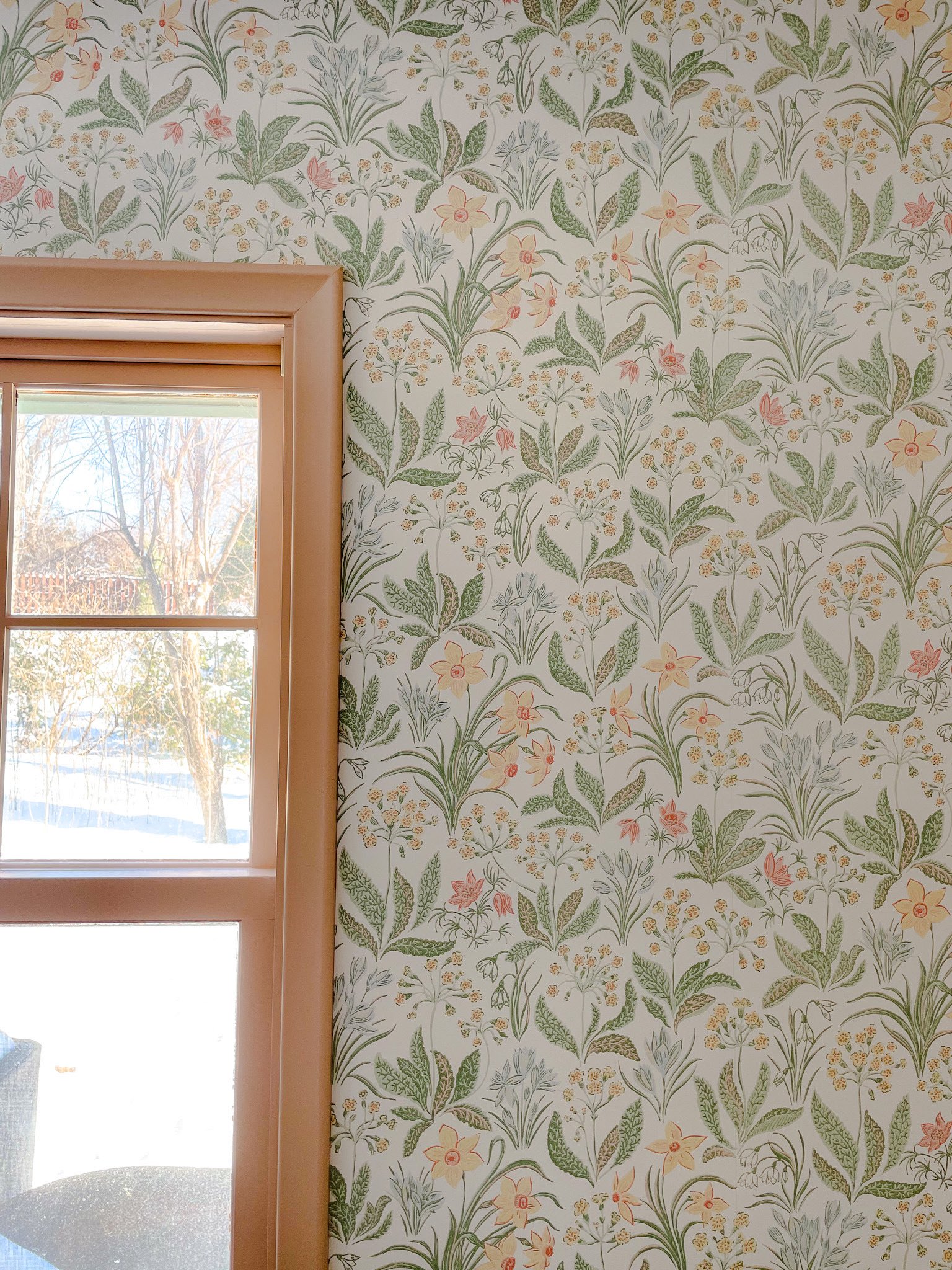 A close-up of a guest room wall with Sandberg Huset i Solen Spring Green wallpaper and Setting Plaster by Farrow & Ball painted trim