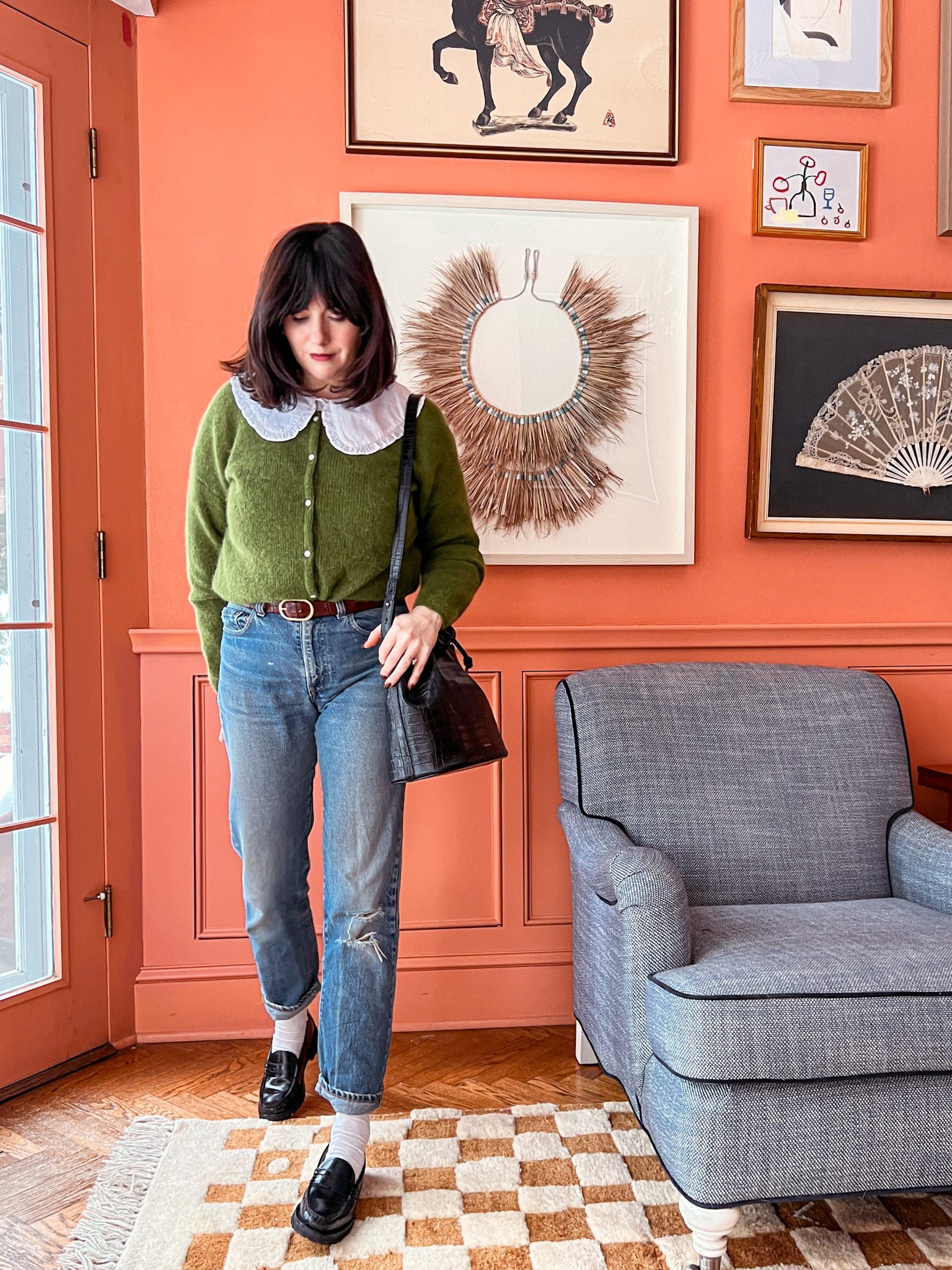 Woman wearing a bright green cardigan in a peach room