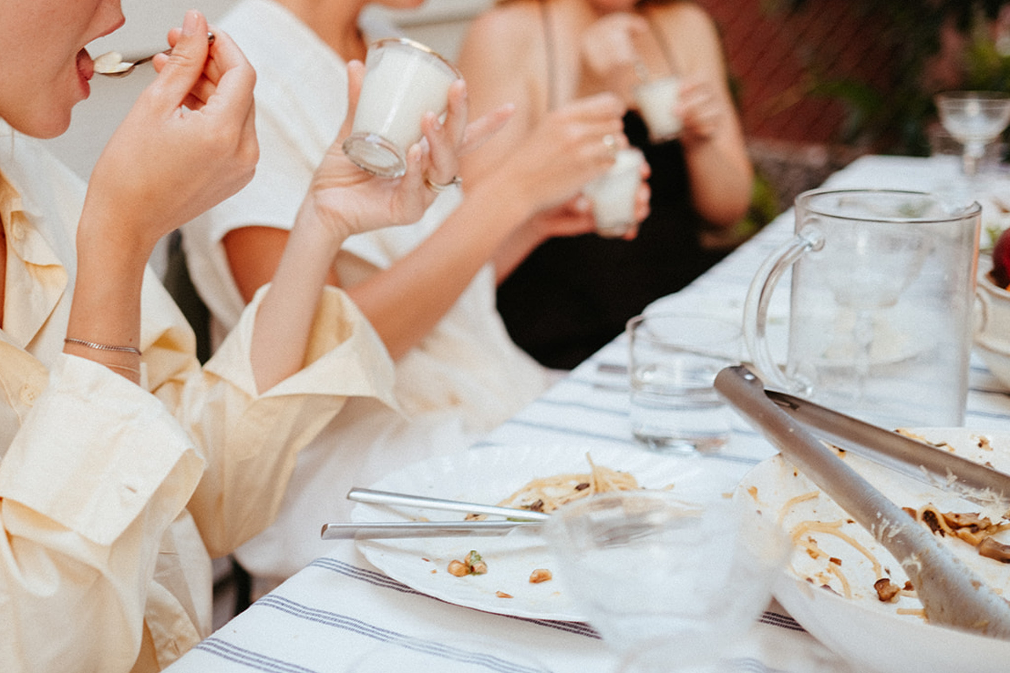 A group of friends gathered around an outdoor dining table are eating lemon panna cotta for dessert.