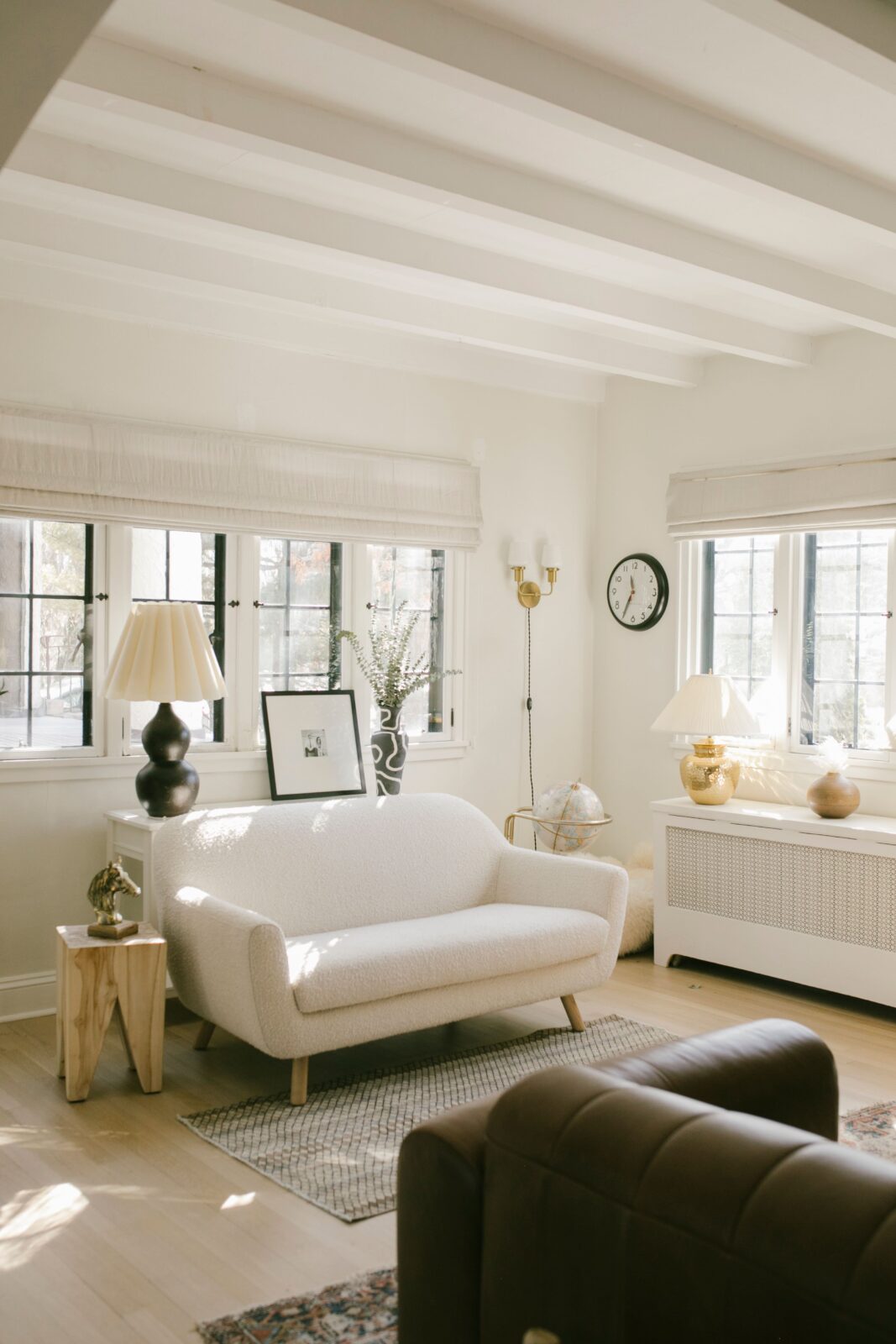 Sunlight flows into a cozy living room. The walls are painted in White Dove by Benjamin Moore, pairing beautifully with neutral decor pieces and layered textures.