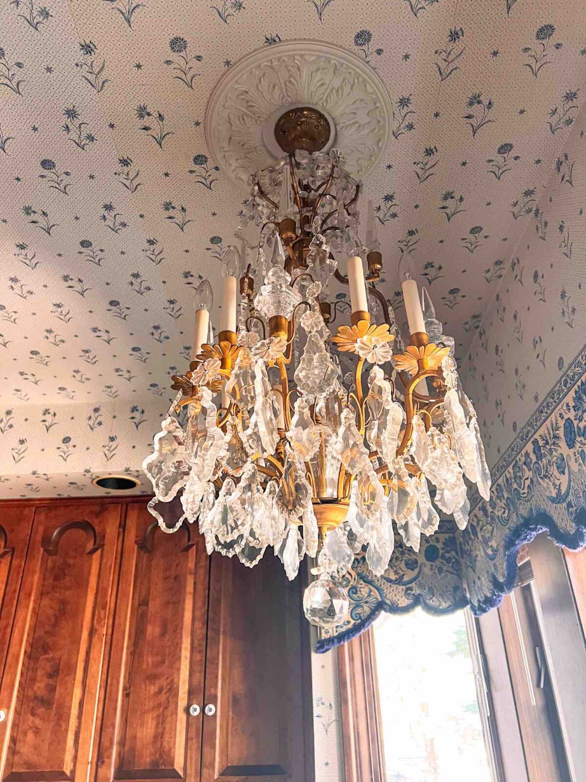 Kitchen ceiling with blue floral wallpaper, ceiling medallion, and chandelier