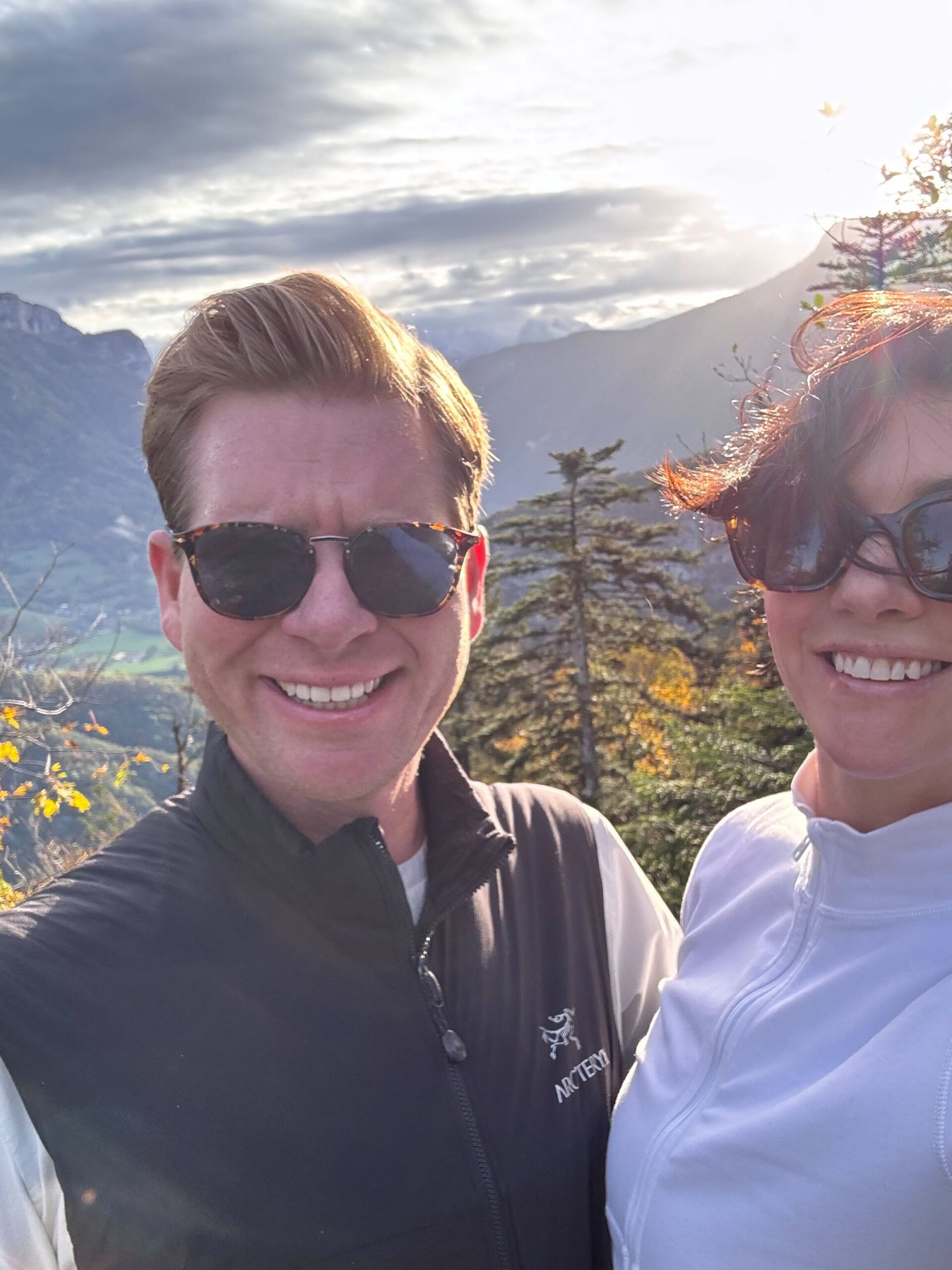 A man and woman stand together smiling while on a hike in the French Alps