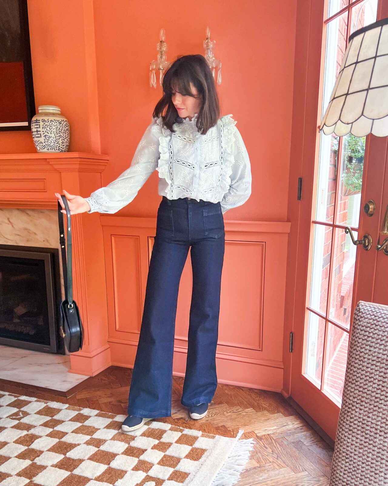 Woman wearing a top with lace detailing, high-rise '70s pants, and black espadrilles.