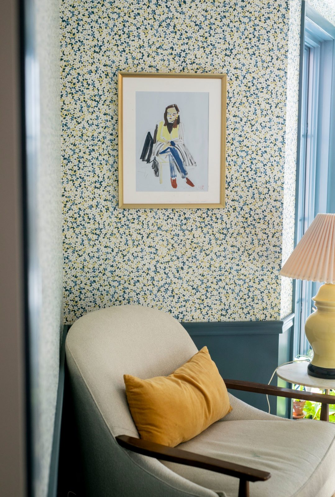 An office features blue-painted wood paneling and floral wallpaper