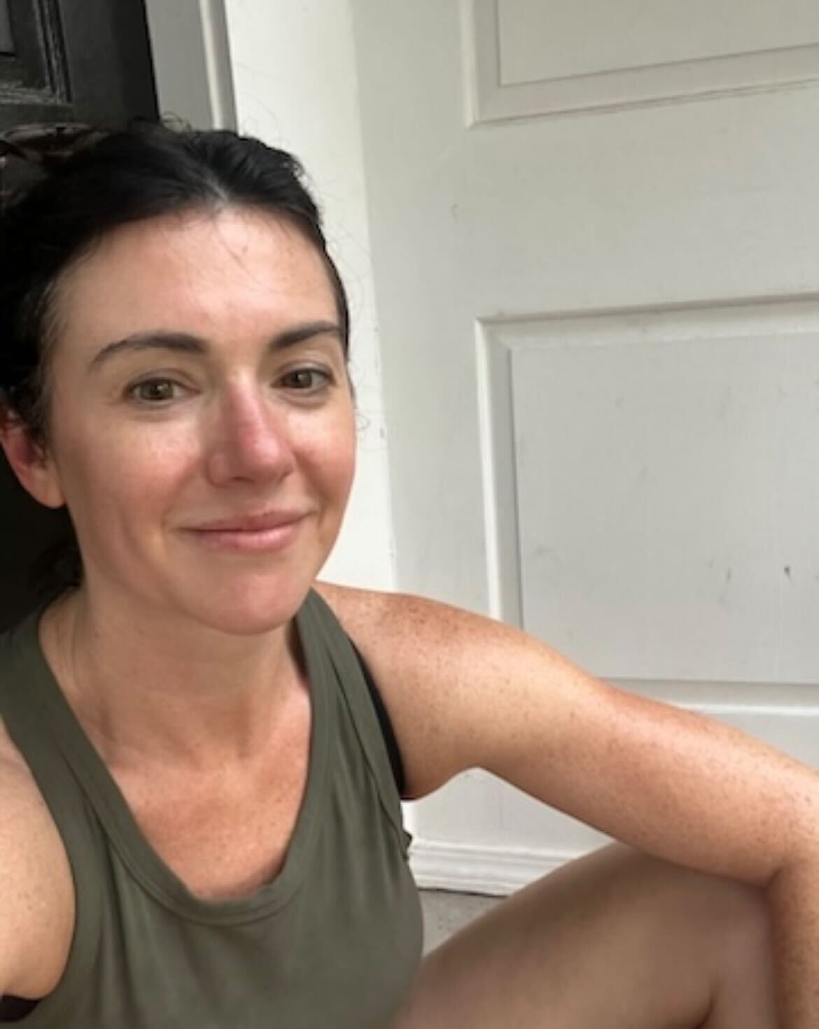 A photo of a woman who's turning 40 sitting on her front step and smiling into the camera.